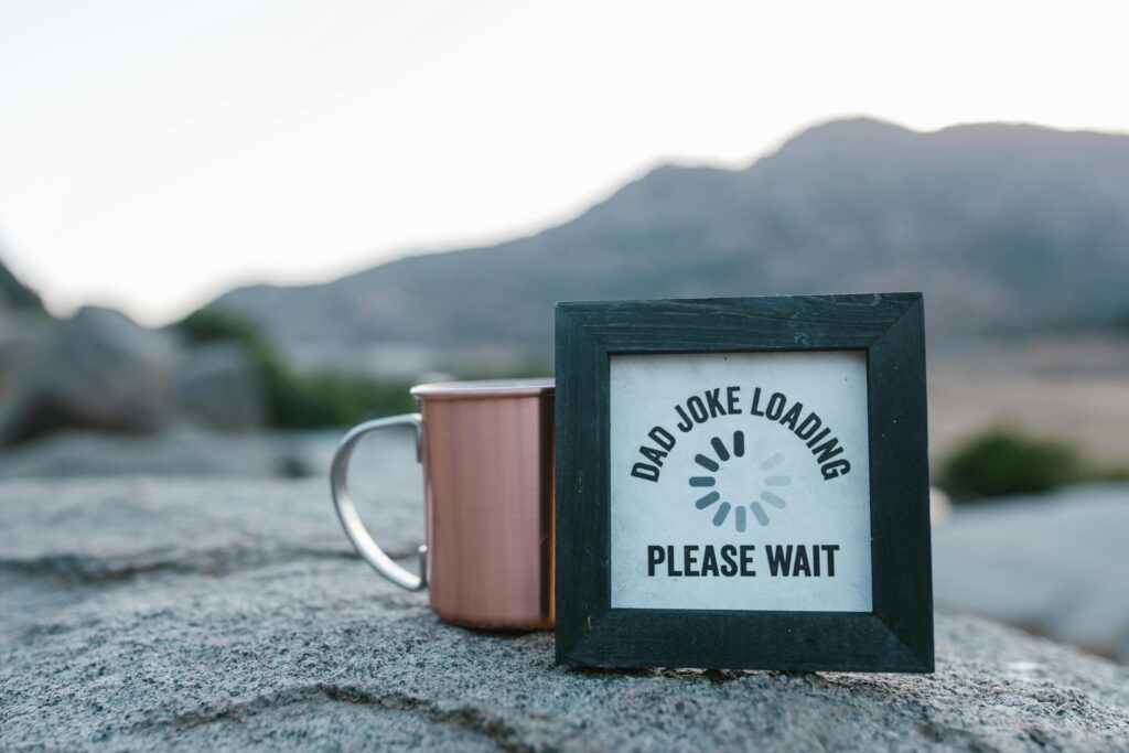 Black wooden frame with “Dad Joke Loading” print leaning on a white mug.